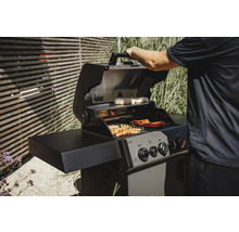 Gasgrill mit Speisen auf dem Rost und einer Person, die den Deckel öffnet