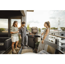 Personen grillen auf dem Balkon mit einem Gasgrill.
