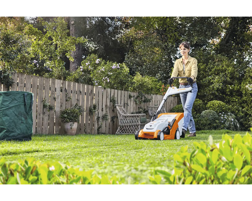 Frau bedient Rasenmäher im Garten