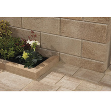 Gestapelte Betonblöcke bilden eine Gartenmauer und ein erhöhtes Blumenbeet mit Bepflanzung.