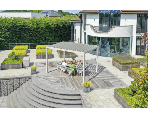 Familie sitzt unter einer Terrassenüberdachung auf einer Holzterrasse in einem Garten.