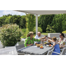 Familie genießt Mahlzeit am Gartentisch unter einer Pergola im Freien