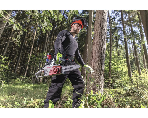 Mann mit Akku-Kettensäge im Wald, ausgestattet mit Helm und Schutzkleidung für sicheres Holzarbeiten.