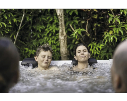 Entspannte Familie genießt ein warmes Sprudelbad im Garten