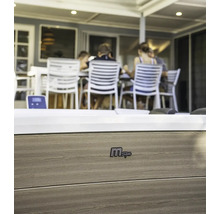 Nahaufnahme eines MSpa Whirlpools mit Holzverkleidung und dem MSpa Logo. Im Hintergrund sitzen Personen an einem Tisch.