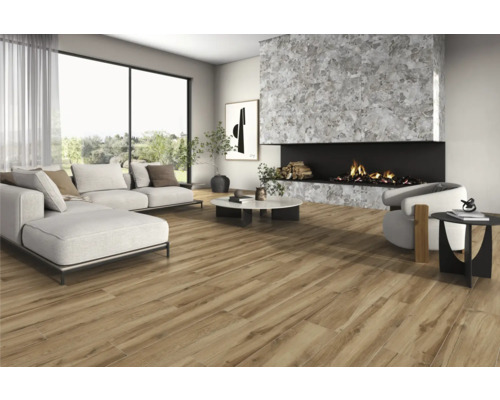 Wohnzimmer mit Sofa, Sessel, Kamin und Bodenfliesen in Holzoptik für ein helles, geräumiges Ambiente.