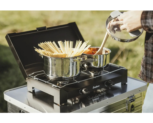 Zwei Kochtöpfe auf einem Campingkocher mit Spaghetti und Soße