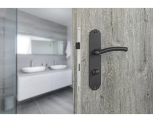 Detailansicht einer Tür mit schwarzer Türklinke vor einem Badezimmer mit Doppelwaschbecken