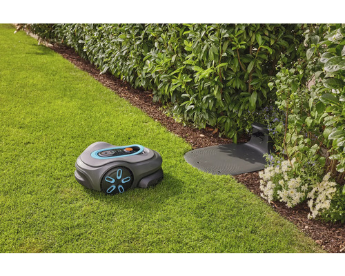 Rasenroboter mit Ladestation auf Rasenfläche neben Büschen