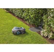 Mähroboter mit Ladestation auf Rasenfläche neben Büschen