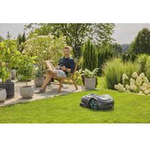 Mann entspannt im Garten mit Rasenmähroboter