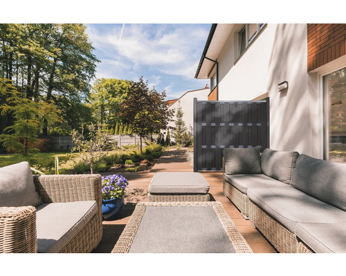 Terrasse mit Rattanmöbeln und Sichtschutzzaun im Garten.
