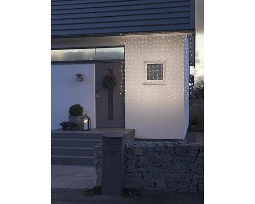 Hausfassade mit Lichterkette, Haustür, Briefkasten und Steinmauer