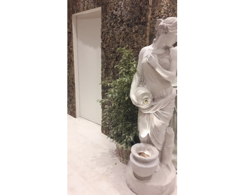 Dekorative Szene mit einer weiblichen Statue, Zimmerpflanze und einer Wand mit Baumrinde