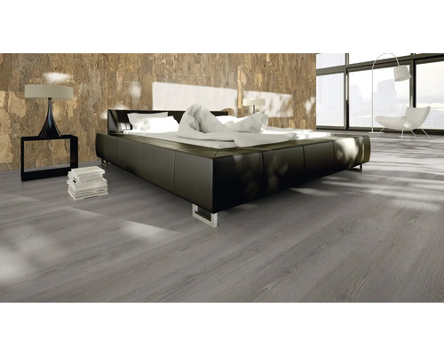 Schlafzimmer mit Doppelbett, Nachttischlampe und grauem Holzboden