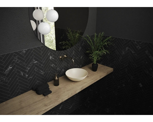 Badezimmer mit Waschbecken, Armatur, Spiegel und dunklen, gefliesten Wänden im Fischgrätenmuster