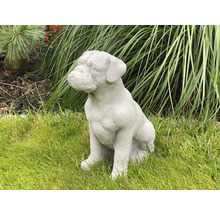 Dekorative Gartenfigur eines sitzenden Hundes auf einer Rasenfläche