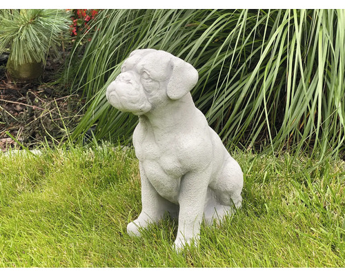 Dekorative Gartenfigur eines sitzenden Hundes auf einer Rasenfläche