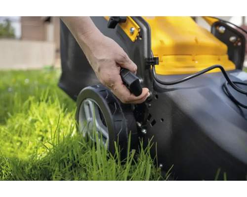 Eine Person bedient einen Rasenlüfter im Garten.