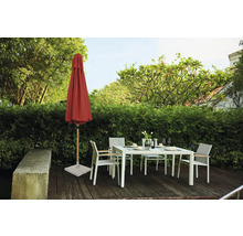 Gartenszene mit geschlossenem Sonnenschirm, Gartentisch und Gartenstühlen auf einer Holzterrasse vor einer grünen Hecke