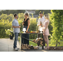 Gesellschaft mit Getränken an Stehtisch mit Holzfach im Garten