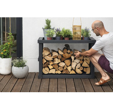 Holzregal mit Holz und Dekorationselementen im Außenbereich, eine Person befüllt das Regal