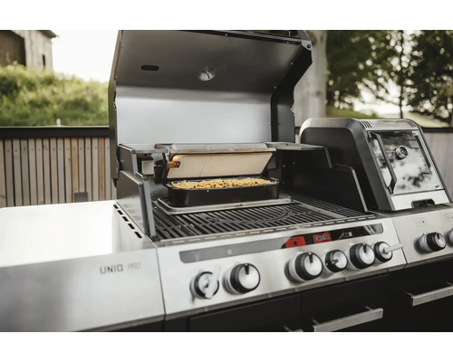 Edelstahl Grill mit Speisen in einer Form unter einem Grill