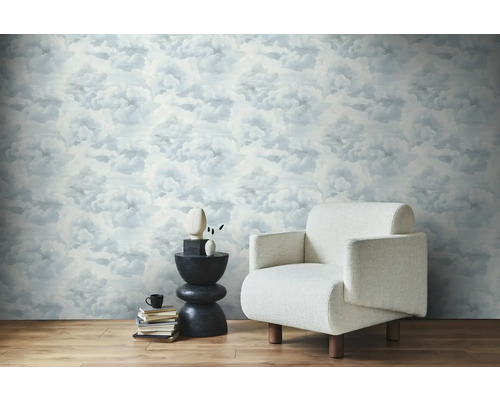 Heller Raum mit Wolkentapete, Sessel und Beistelltisch.