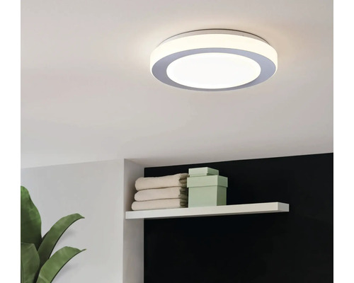 Runde Deckenleuchte im Badezimmer mit Handtüchern und Schachteln im Regal