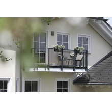 Außenansicht eines Hauses mit Balkon, Balkonmöbeln und Blumenkästen