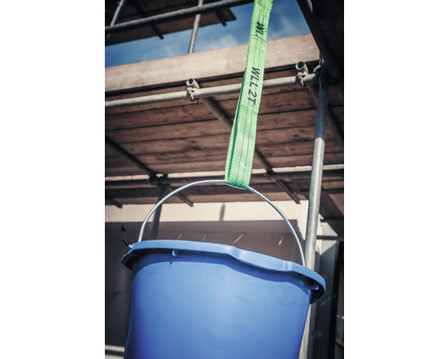 Blauer Eimer hängt an einem grünen Hebegurt vor einem Baugerüst.