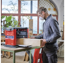 Mann arbeitet mit einer Einhell Hobelmaschine an einem Holzstück in einer Werkstatt.