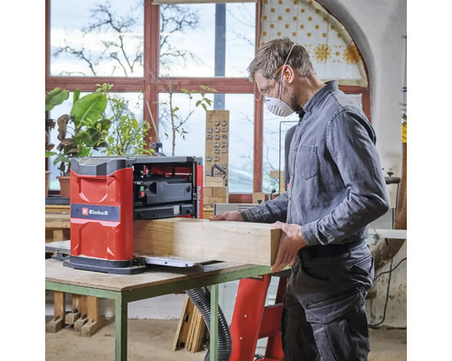 Mann arbeitet mit einer Einhell Hobelmaschine an einem Holzstück in einer Werkstatt.