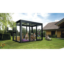 Familie entspannt sich in einem modernen Gartenhaus mit Glaswänden und schwarzem Rahmen auf einer Rasenfläche.