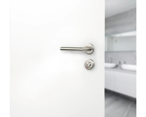 Weiße Tür mit Edelstahl-Türgriff und Badezimmer im Hintergrund