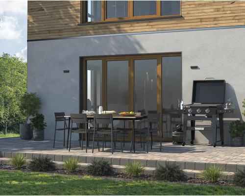 Terrasse mit Grill, Gartentisch und Gartenstühlen vor Hauswand