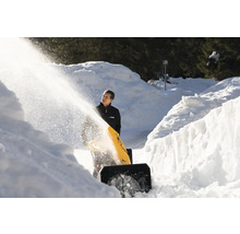Eine Person benutzt eine Schneefräse, um einen Weg von Schnee zu befreien.
