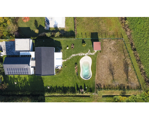 Luftaufnahme eines Hauses mit Garten, Pool und Solarpanelen auf dem Dach