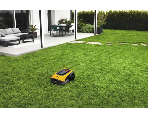Gelber Rasenmähroboter auf einer Rasenfläche mit Haus im Hintergrund