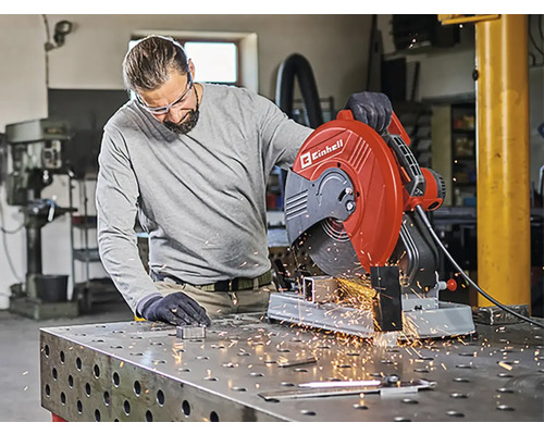 Ein Mann bedient eine Einhell Metalltrennsäge in einer Werkstatt, Funken fliegen.