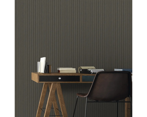 Bürobereich mit Schreibtisch, Büchern, Schreibmaschine und Stuhl vor einer Wand mit Holzpaneelen