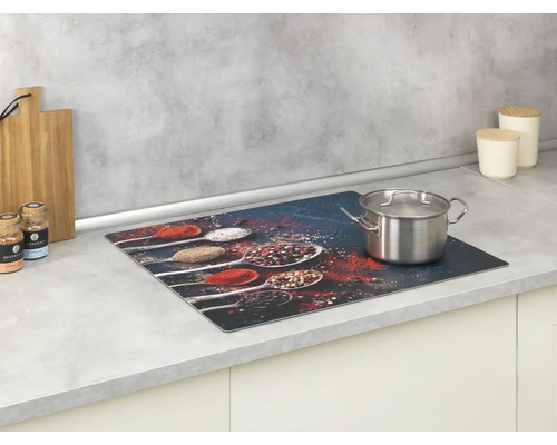 Glaskeramikfeldabdeckung mit Gewürzmuster und Kochtopf auf einer Küchentheke.