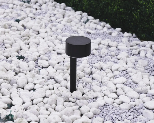 Schwarze Solarleuchte im Garten zwischen weißen Steinen