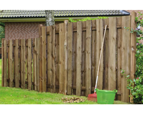 Holzzaun im Garten mit Rechen und Gartenkorb