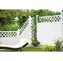 Gartenansicht mit weißem Zaun, Liegestuhl und grüner Bepflanzung