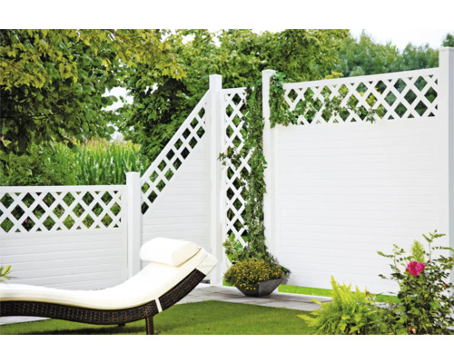 Gartenansicht mit weißem Zaun, Liegestuhl und grüner Bepflanzung