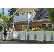 Person übergibt ein Paket vor einem Haus mit weißem Zaun