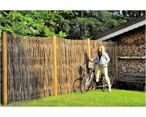 Naturzaun aus Weidenruten mit Frau und Fahrrad im Garten