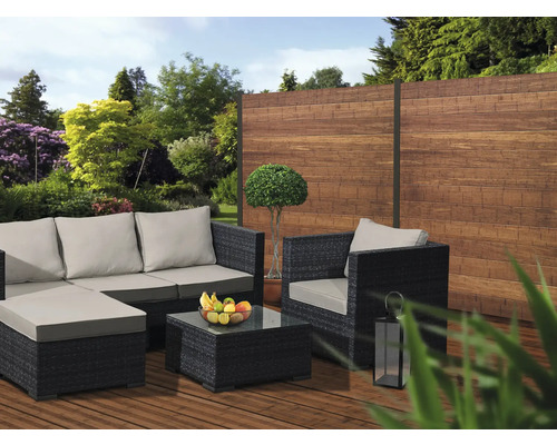 Gartenlounge-Set mit Sofa, Sessel und Tisch auf einer Terrasse vor einem Holzzaun