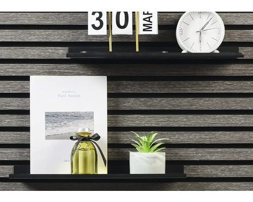 Dekorative Gegenstände auf einem Regal: Kalender, Uhr, Notizbuch, Duftflasche und Zimmerpflanze.